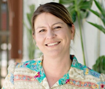 Woman smiling with festive floral arrangement for holiday decorating.