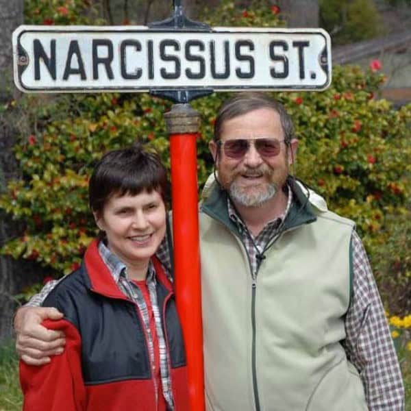 NARCISSUS ST. street sign with two gardeners smiling outdoors.