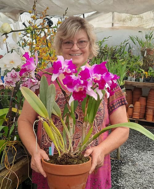 Orchid plant in a terracotta pot held by Linda Thorne at the Charlotte Garden Club.