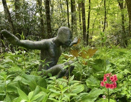 Child playing in lush garden with greenery and pink flowers, enjoying outdoor activities.