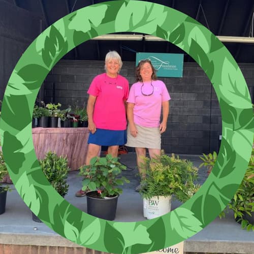 Two women from Charlotte Garden Club at plant sale with greenery.